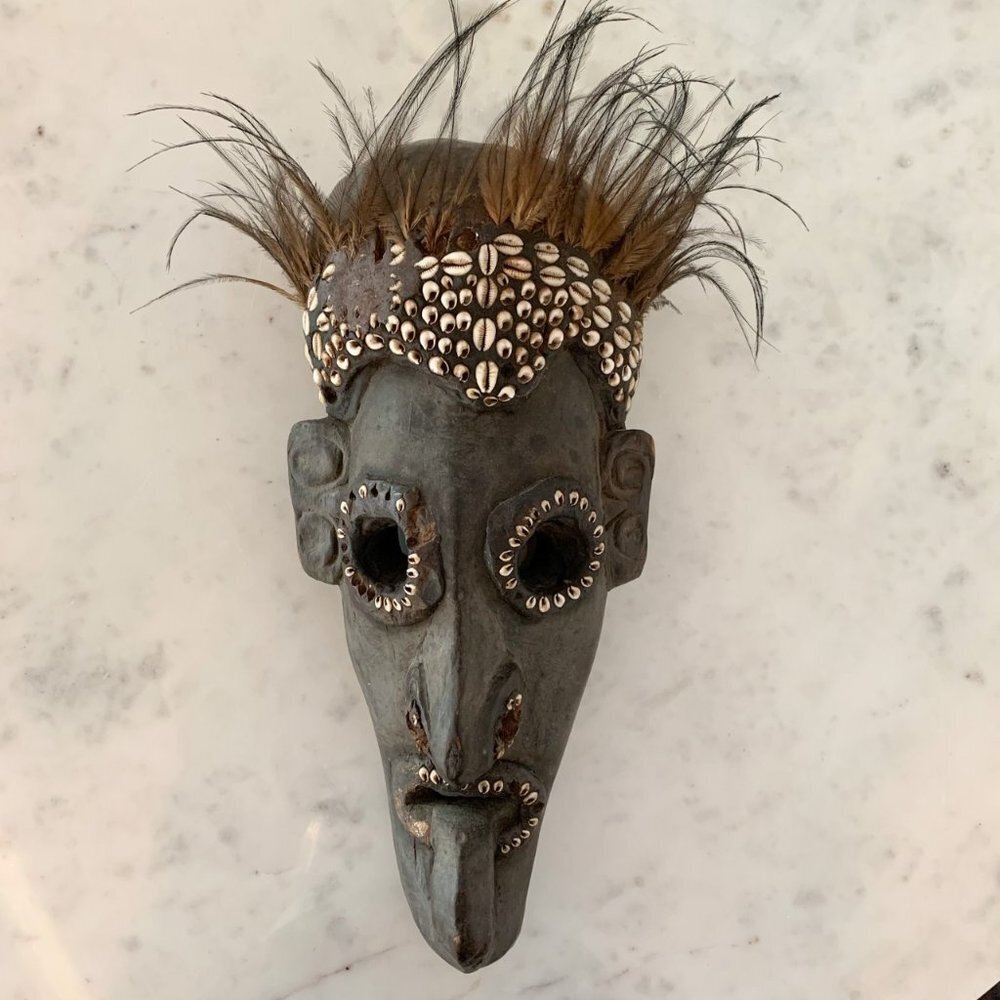 Vintage African wood mask with cowrie shells and feathers